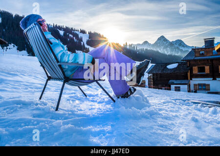 Woman relaxing in deck chair after skiing Stock Photo