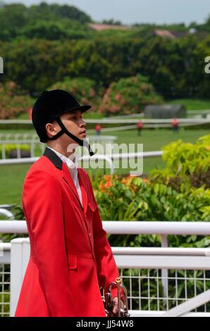 Chinese bugler in jockey gear begins Emirates Singapore Derby at Kranji Turf Club horse race Stock Photo