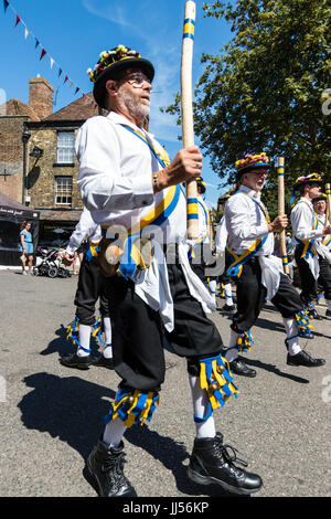 Traditional English folk dancers, Yateley Morris side dancing in the street in medieval town of Sandwich during folk and ale festival. Holding poles. Stock Photo