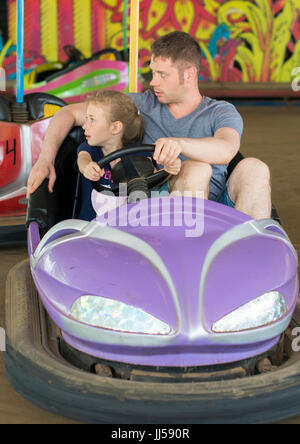Father and daughter having fun on bumper car in amusement park. Stock Photo