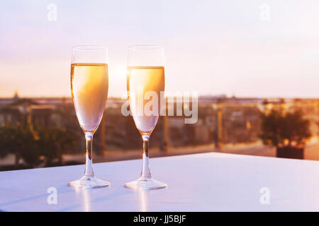 two glasses of champagne at rooftop restaurant with view of city skyline, luxury romantic dinner for couple Stock Photo