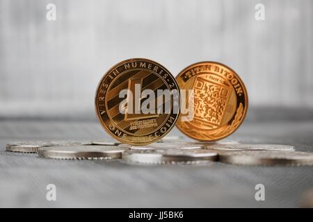 Cryptocurrency physical gold litecoin coin and gold titan bitcoin coin on silver money. Stock Photo