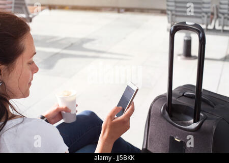 woman passenger using mobile internet or wifi on her smartphone in the airport or modern train station Stock Photo