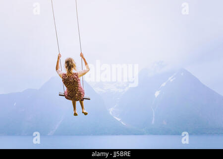 happiness concept, happy girl child on the swing on beautiful mountain landscape background Stock Photo