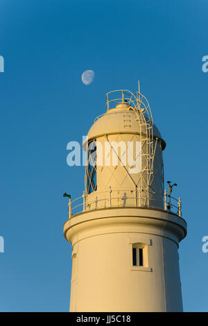 The moon behind the iconic Portland Bill lighthouse, Portland, England, UK Stock Photo