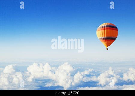 inspiration or travel background, fly above the clouds, colorful hot air balloon in blue sky Stock Photo