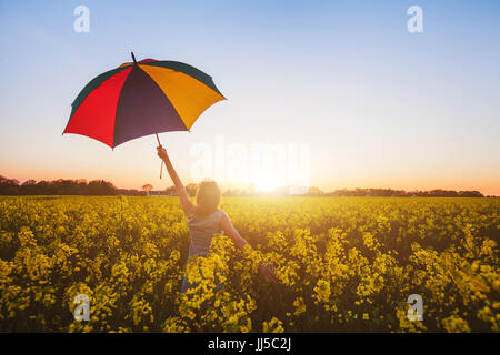 happy woman with colorful umbrella at sunset flower field, joy concept Stock Photo