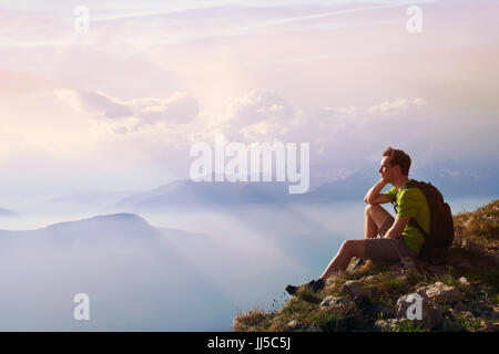 man sitting on top of mountain, achievement or opportunity concept, hiker looking forward on beautiful panoramic landscape Stock Photo