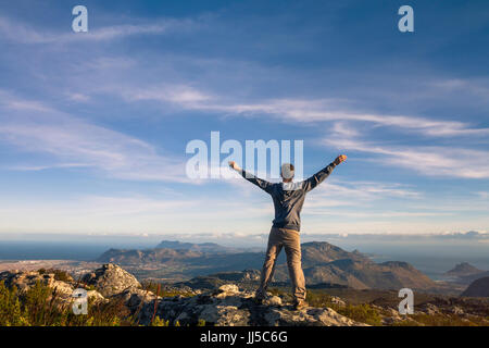 man standing with raised hands on top of Table mountain in Cape Town, South Africa Stock Photo