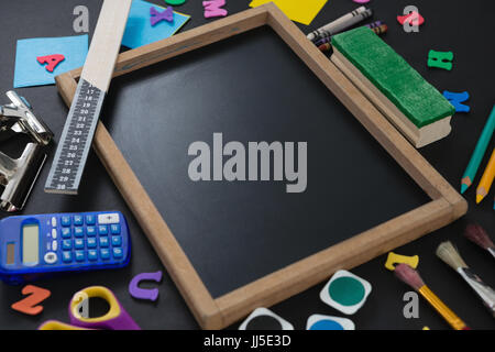 Blank slate surrounded by various school supplies on black background Stock Photo