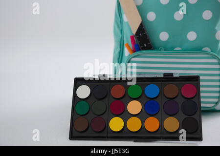 Close-up of schoolbag with various supplies and palette on white background Stock Photo