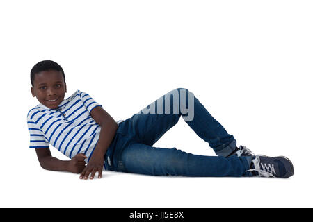 Smiling boy lying on floor against white background Stock Photo