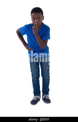 Portrait of boy with finger on lips against white background Stock Photo