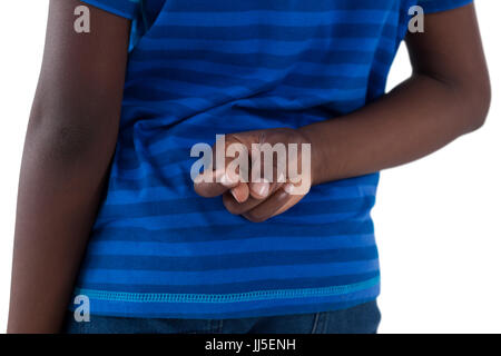 Mid-section of boy holding his fingers crossed against white background Stock Photo