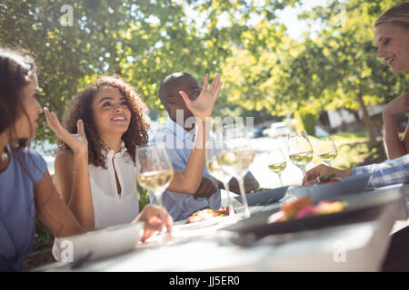 Happy friends interacting with each other while having meal in restaurant Stock Photo