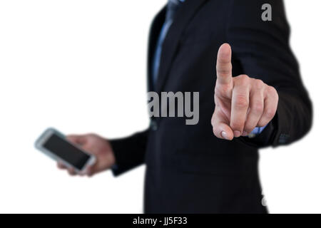 Mid section of businessman holding smartphone while using invisible interface against white background Stock Photo