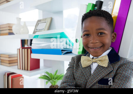 Close up portrait of smiling boy imitating as businessman standing in office Stock Photo