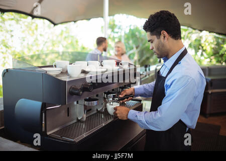 Waiter making cup of coffee from espresso machine in restaurant Stock Photo