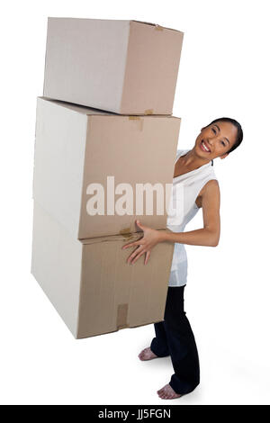 Portrait of smiling businesswoman carrying stack of cardboard boxes while standing against white background Stock Photo