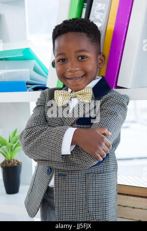 Portrait of boy imitating as businessman standing with arms crossed against self in ffice Stock Photo