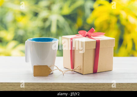 Coffee cup and gift box on wood table with sunlight. Stock Photo
