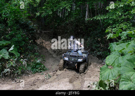 A Russian man rides an all-terrain quad bike vehicle ATV in a muddy mountainous area in the south eastern side of the island of Sakhalin, in the Pacific Ocean. Russia Stock Photo