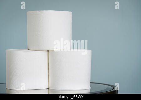 Stack of toilet paper rolls on mirrored table. Stock Photo