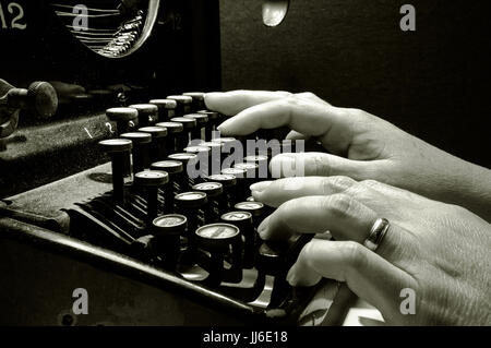 Hands typing on old typewriter keyboard B&W image Stock Photo
