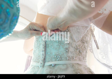 A bride being helped into her dress from behind Stock Photo