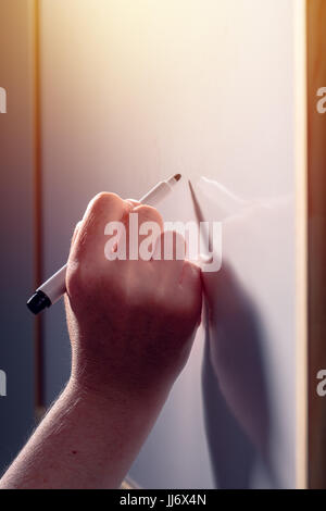 School teacher writing on classroom whiteboard during the lecture, selective focus Stock Photo