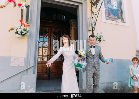 The horizontal view of the bride throwing the candies near the church. Stock Photo