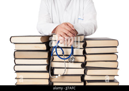 Senior doctor in white tunic and stethoscope leaning on many stacked books and textbooks. Stock Photo