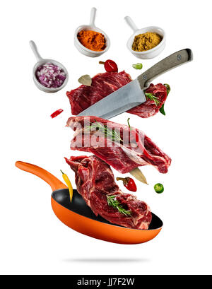 Flying raw steaks, with ingredients for cooking, from pan. wooden bowls with spices. Concept of food preparation. Isolated on white background. Extra  Stock Photo