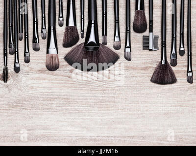 Set of various natural bristle makeup brushes. Professional tools of make-up artist on shabby wooden surface. Copy space Stock Photo