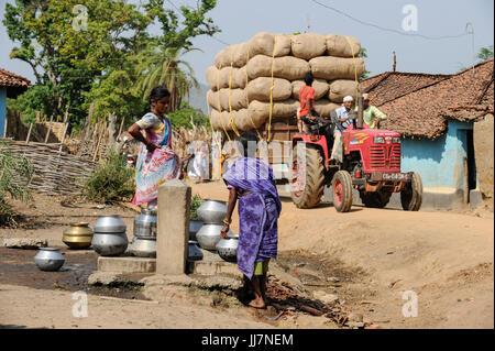 INDIA Chhattisgarh, Bastar, tribal Gond women at water pump in village, Mahindra tractor transporting jute bags, the area is under pressure from maoist terror groups, so called Naxalites Stock Photo