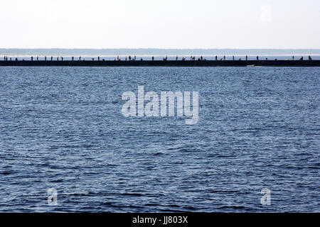 Many anglers are standing on a mole in the Baltic Sea in Bolderāja Riga and catch fish Stock Photo