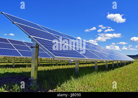 Solar panels on field. Clear sky with a few small clouds on background. Stock Photo
