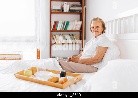 Happy elderly woman having breakfast in bed Stock Photo