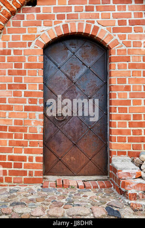 Old metal door in a brick wall on the castle hill in Vilnius Stock Photo
