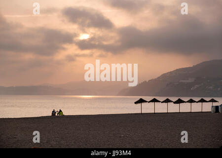 Two people at a table enjoying drinks alone on Easter Sunday on the long beach at Salobreña, Province of Granada, Spain Stock Photo