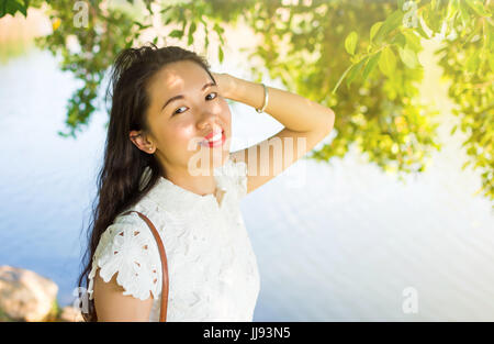 Girl standing by the lake and enjoying the wind breezing her face Stock Photo