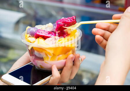 Female eating tropical fruit salad on the street Stock Photo