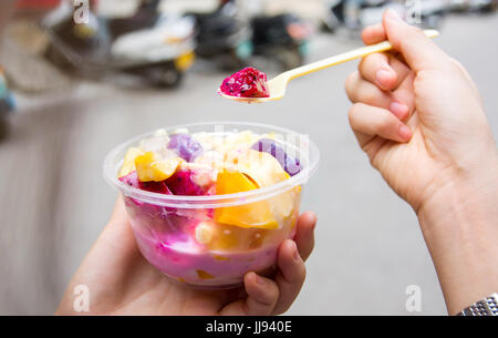 Female eating tropical fruit salad on the street Stock Photo