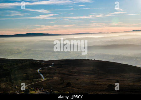 Hill path at high level in heather moorland with misty valley. Stock Photo