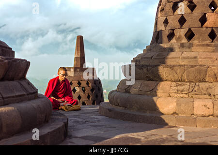 Red robed monks praying at sunrise at the world heritage site Borobudur Buddist temple. Stock Photo