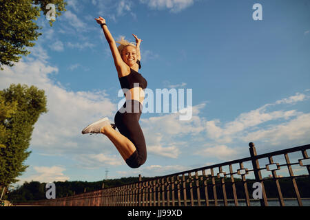 Jumping sports girl on the blue sky. Stock Photo