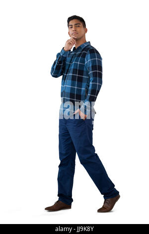 Portrait of man with hand on chin standing against white background Stock Photo