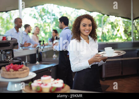 Portrait of waitress holding coffee tray in outdoor cafe Stock Photo