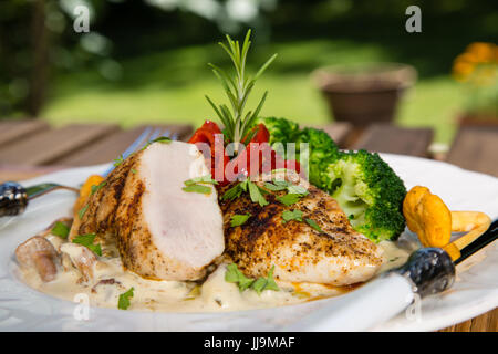 Grilled chicken, cream sauce with mushrooms chanterelles, broccoli and roasted red peppers. Healthy balanced food concept. Stock Photo