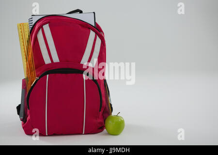 Close-up of schoolbag with various supplies and apple on white background Stock Photo